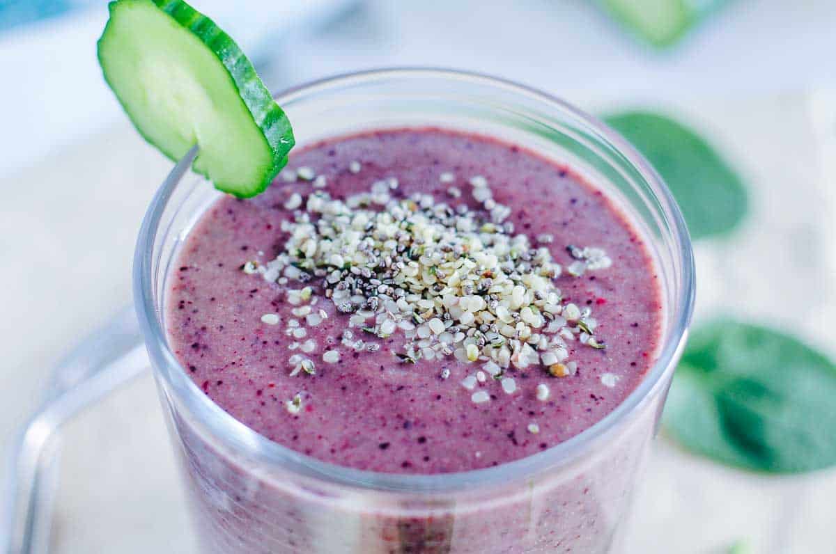 A glass filled with a blueberry spinach smoothie