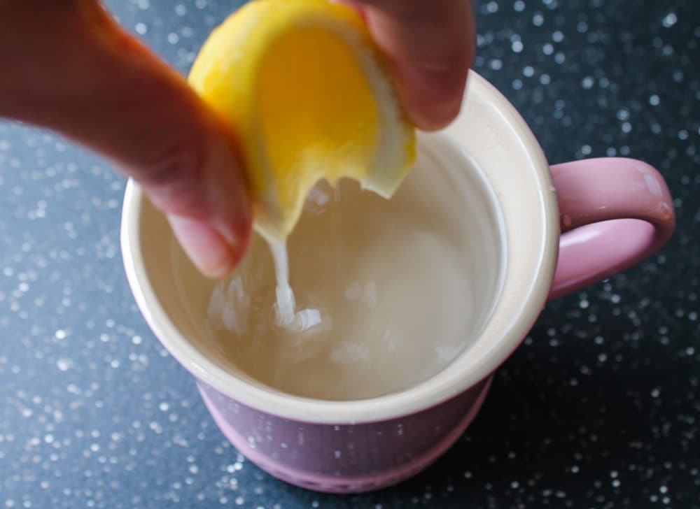 lemon being squeezed into hot water.