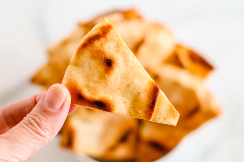 a hand holding a homemade pita chip