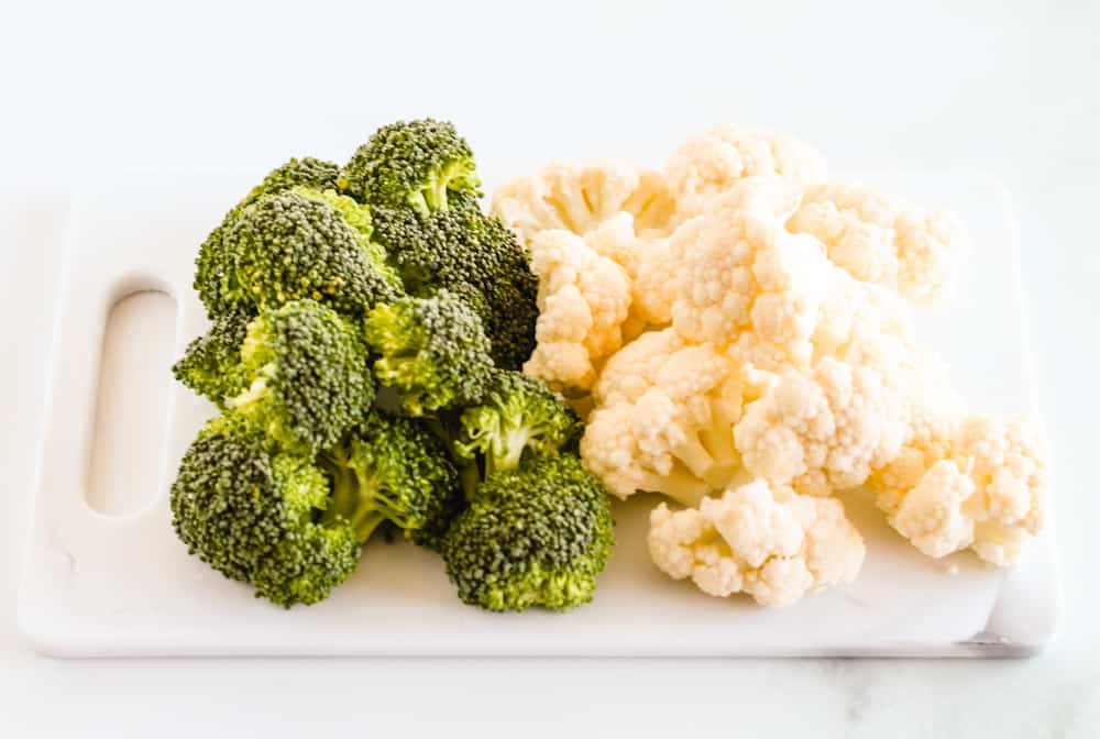 raw florets of cauliflower and broccoli on a cutting board