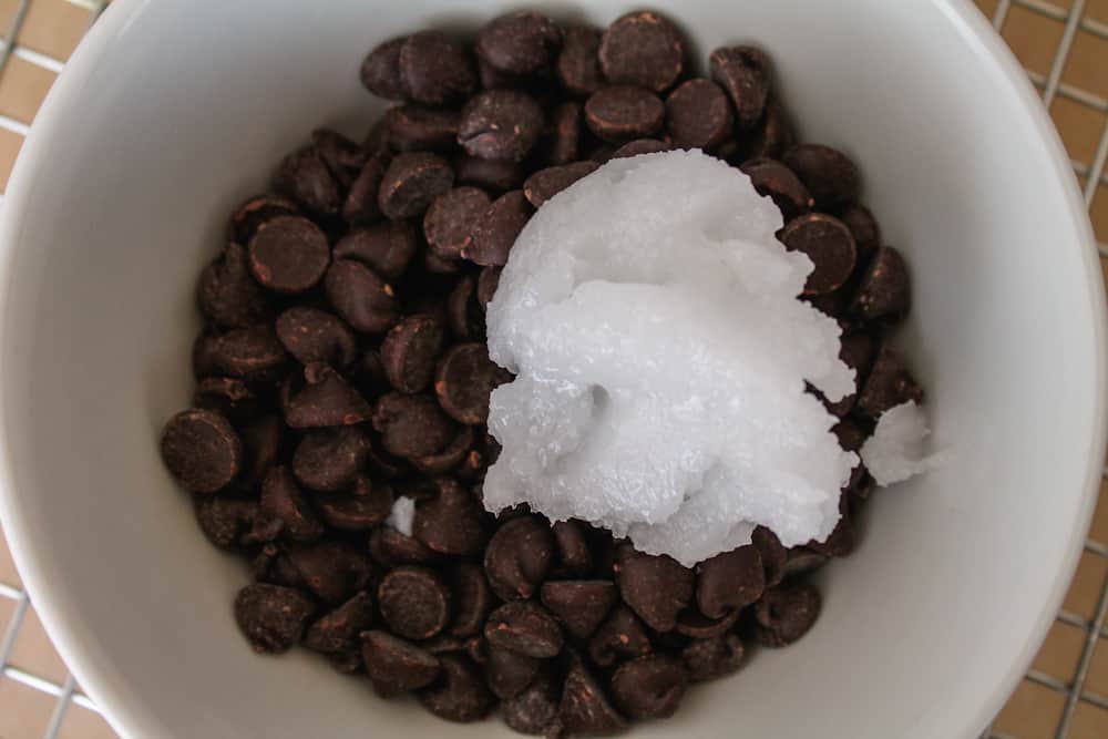 chocolate chips in a bowl with a dollop of coconut oil.