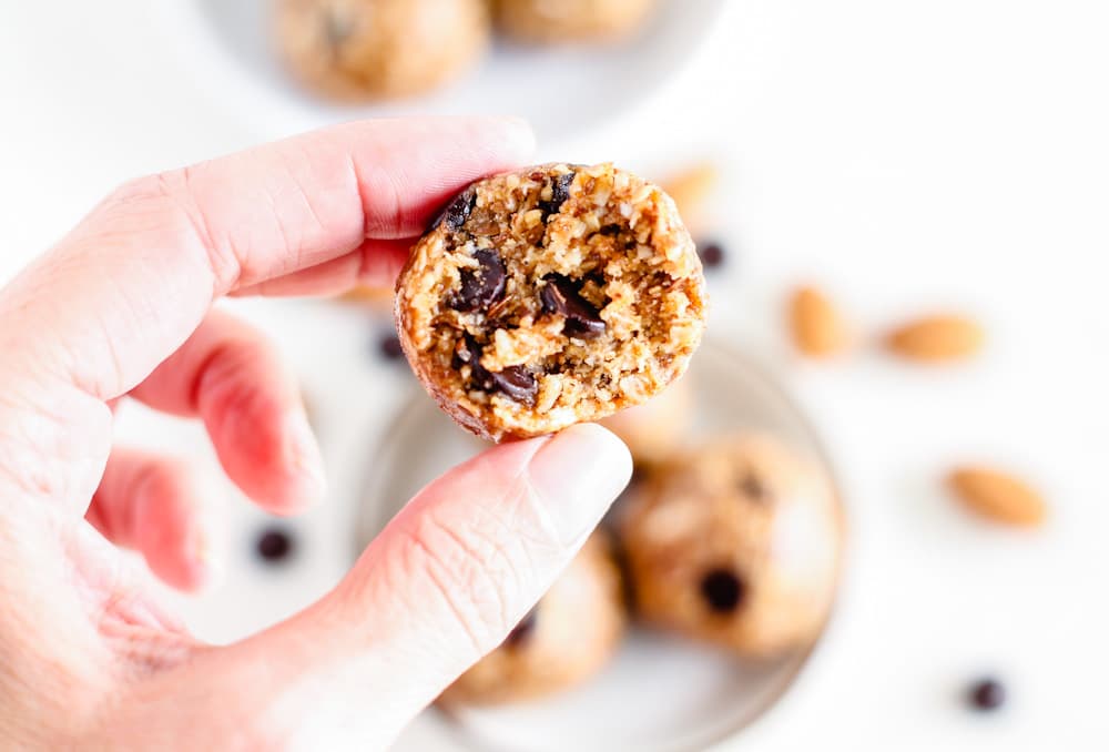 a hand holding an almond butter energy bite.