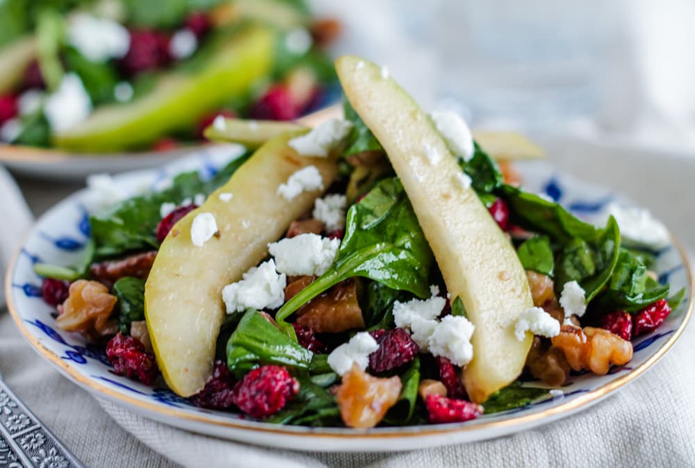 spinach salad with cranberries on a plate.