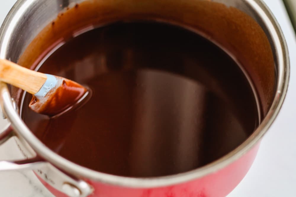a spatula stirring a chocolate mixture in a saucepan.