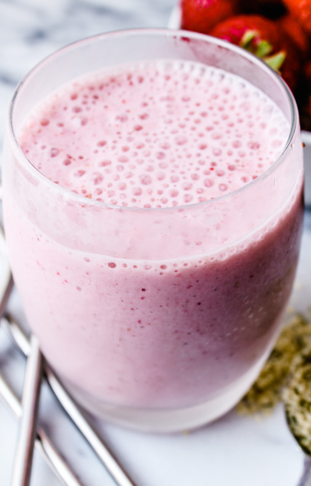 a glass with a healthy strawberry smoothie in it.