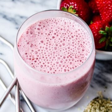 a glass with a healthy strawberry smoothie in it.
