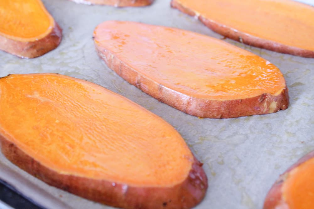 slices of sweet potato on a parchment lined baking sheet.