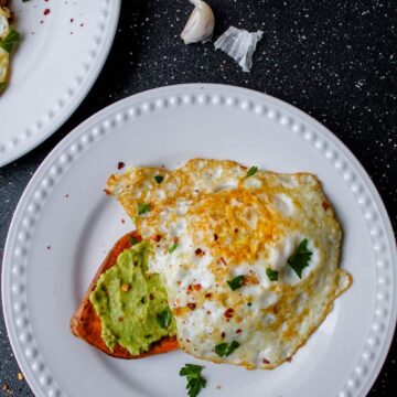 a plate of sweet potato toast topped with mashed avocado and a fried egg.