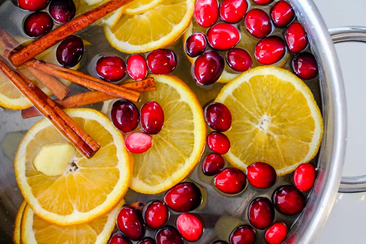oranges, cranberries, and spices in a pot of water.