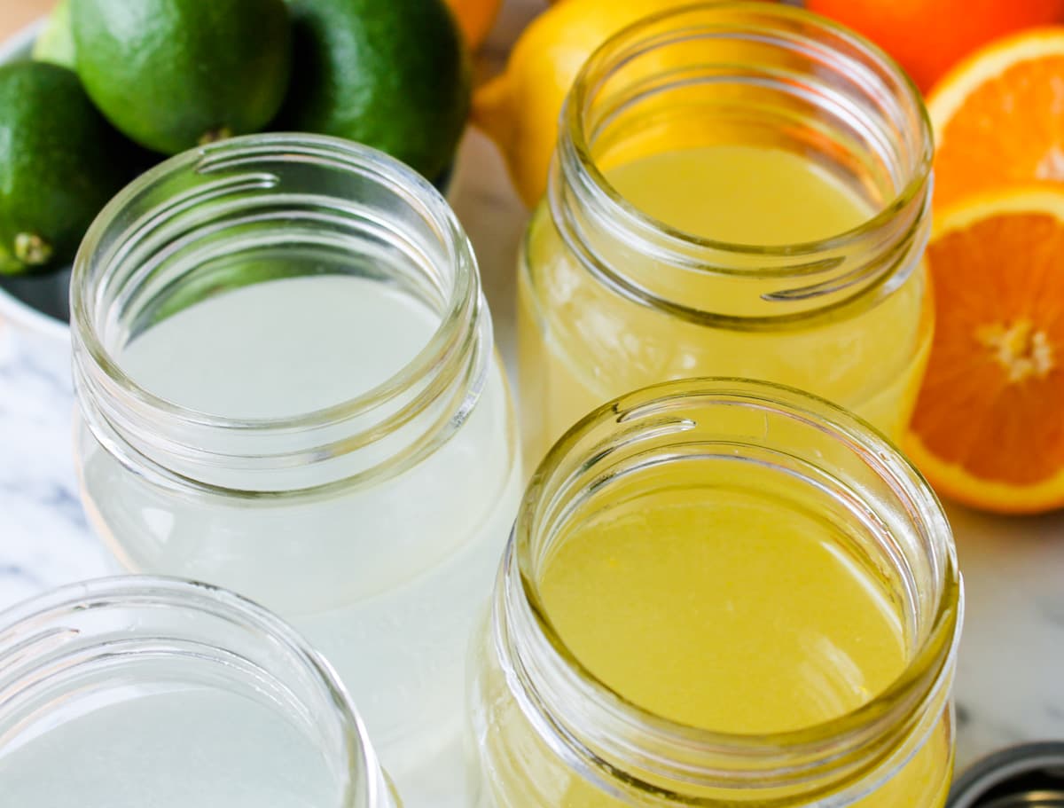 jars of homemade gatorade on a counter with orange and lemon lime.