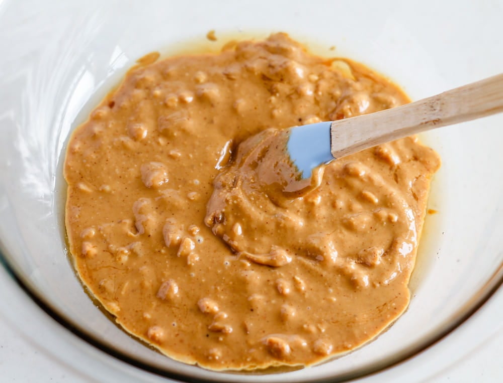 a bowl of peanut butter and maple syrup being stirred together.