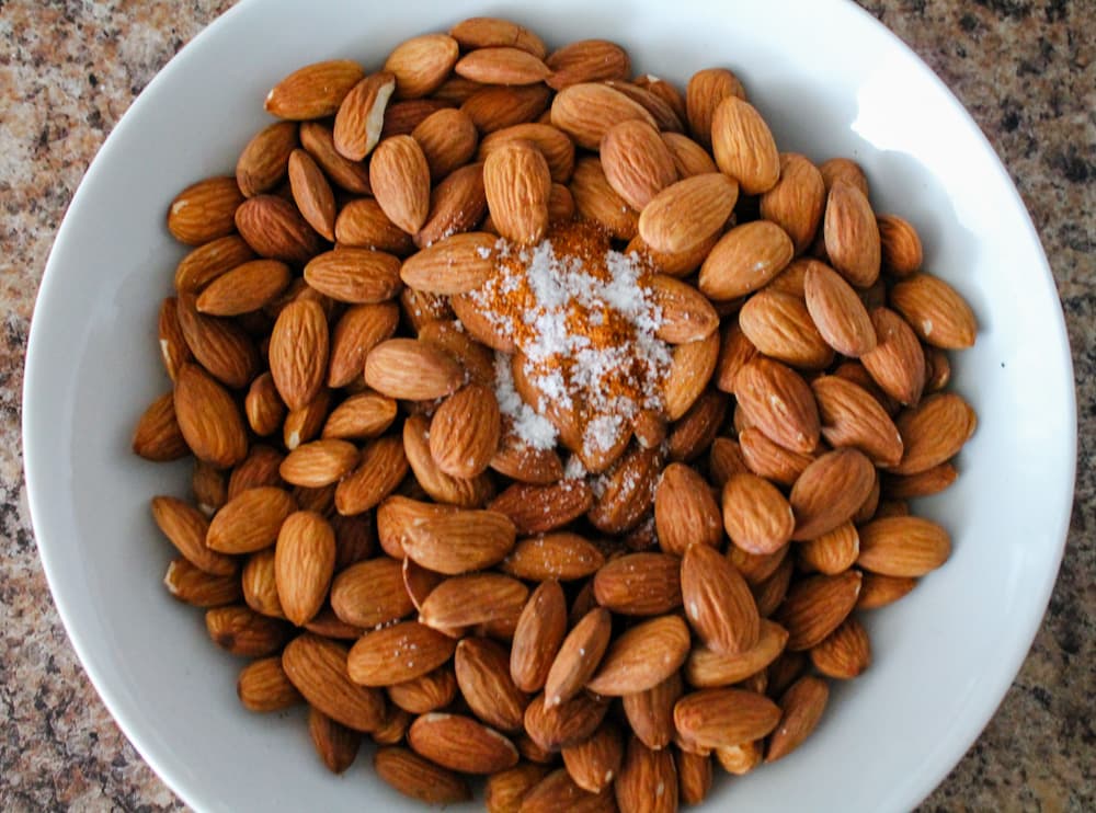 a bowl of almonds with a pinch of salt and cayenne pepper.