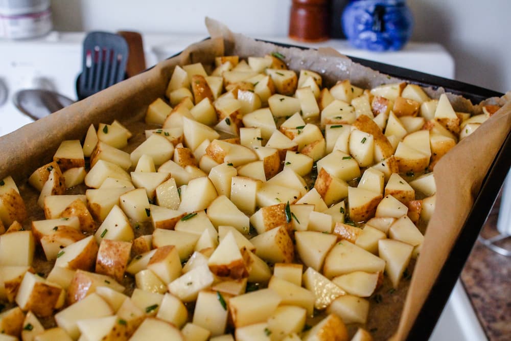 chopped potatoes on a baking sheet about to be put into a hot oven.