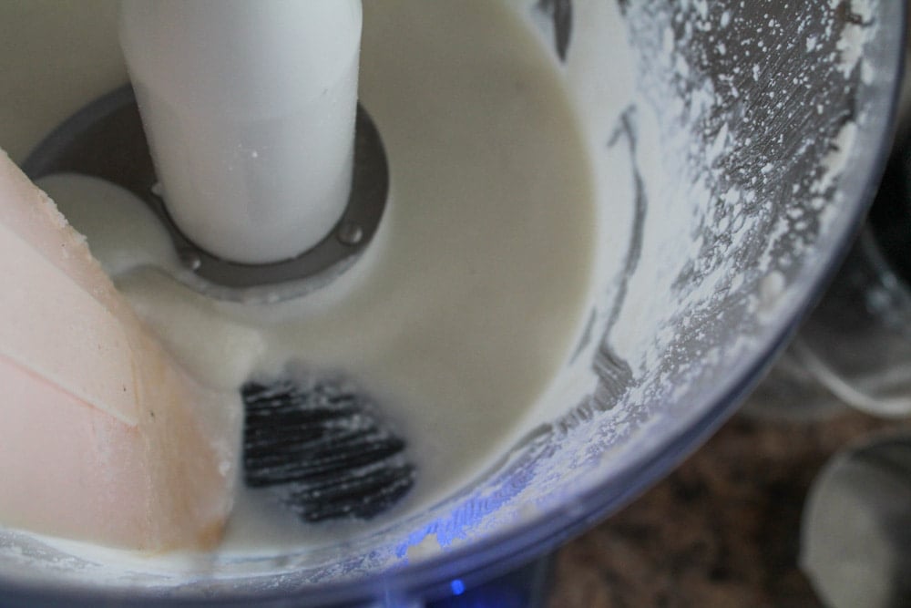 a spatula scraping down the sides of a food processor.