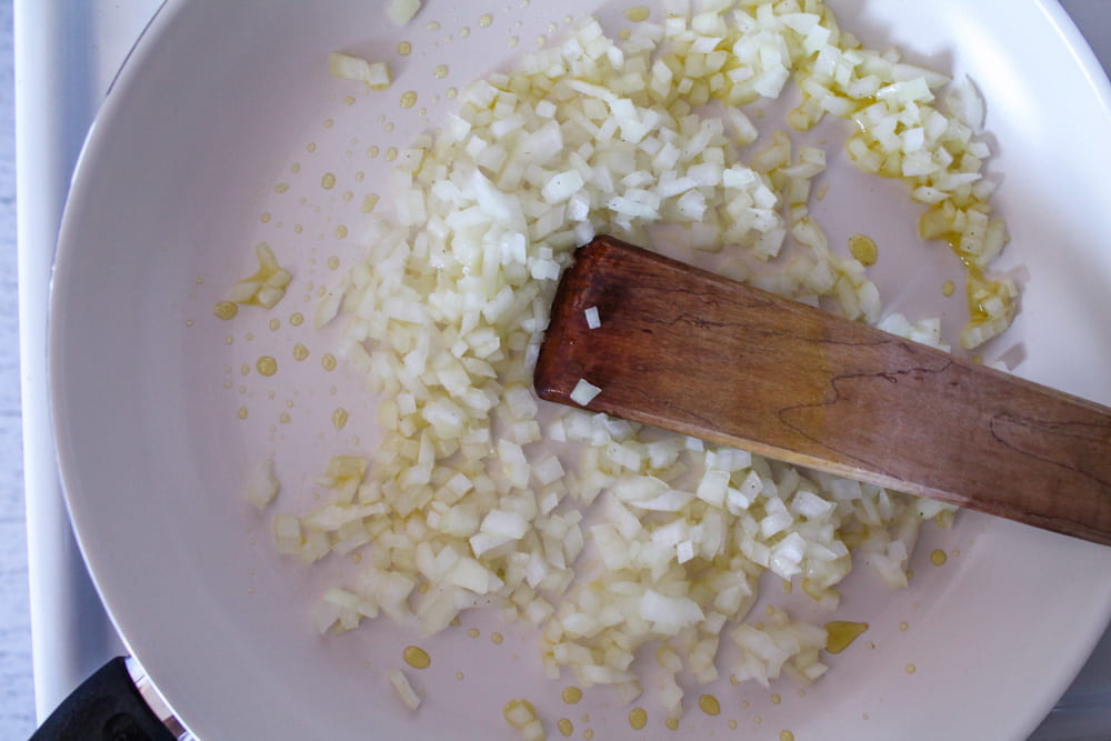 diced onions being sauteed in a pan.