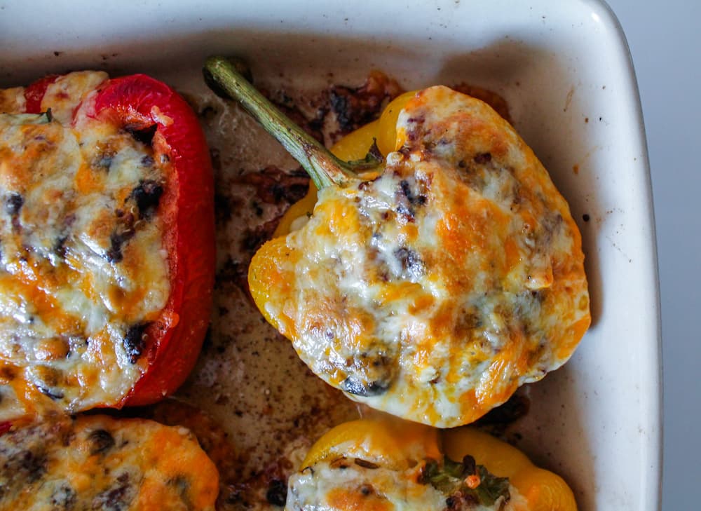 vegetarian stuffed peppers topped with cheese in a baking dish.