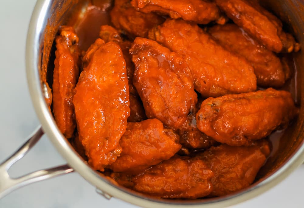 baked chicken wings in a saucepan coated with buffalo sauce.