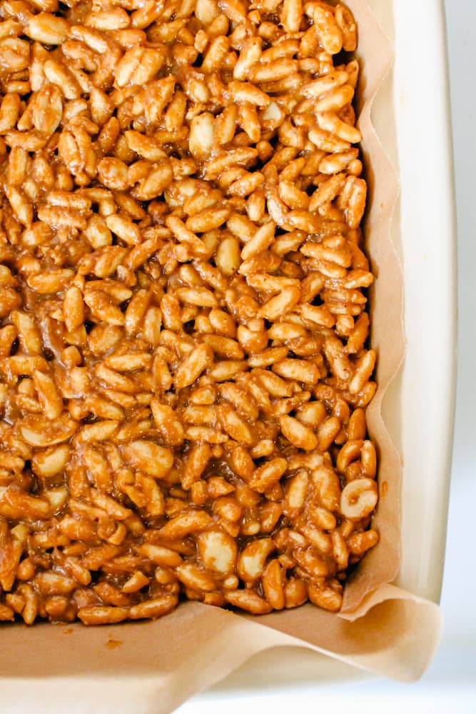peanut butter and rice crispy mixture firmly packed into a parchment lined pan.