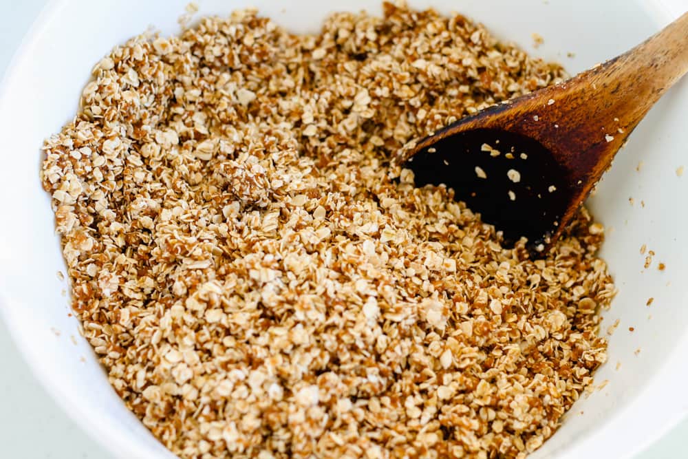 oats, honey and coconut sugar being stirred in a bowl.