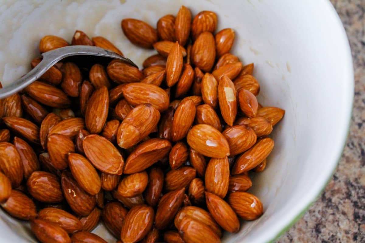 almonds being coated with warm maple syrup.