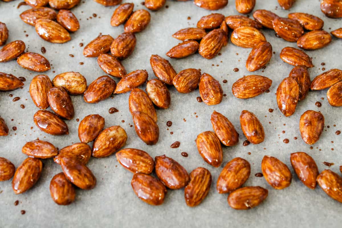 almonds spread out on a parchment paper lined baking sheet.