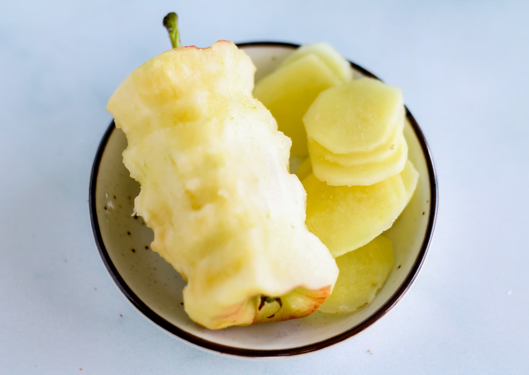an apple core and sliced ginger on a plate.