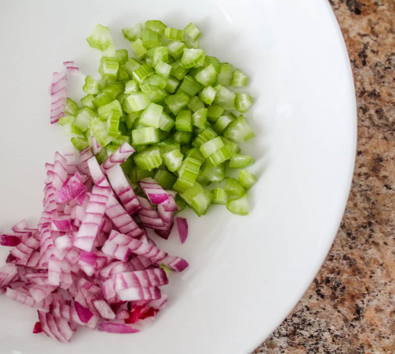 chopped celery and red onion in a bowl.