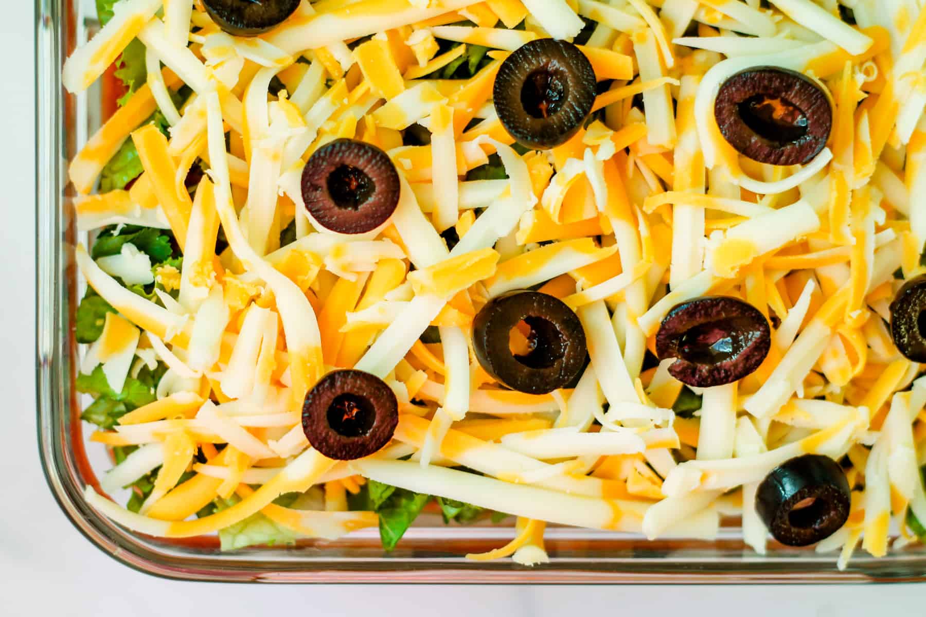 sliced black olives on top of shredded cheese.