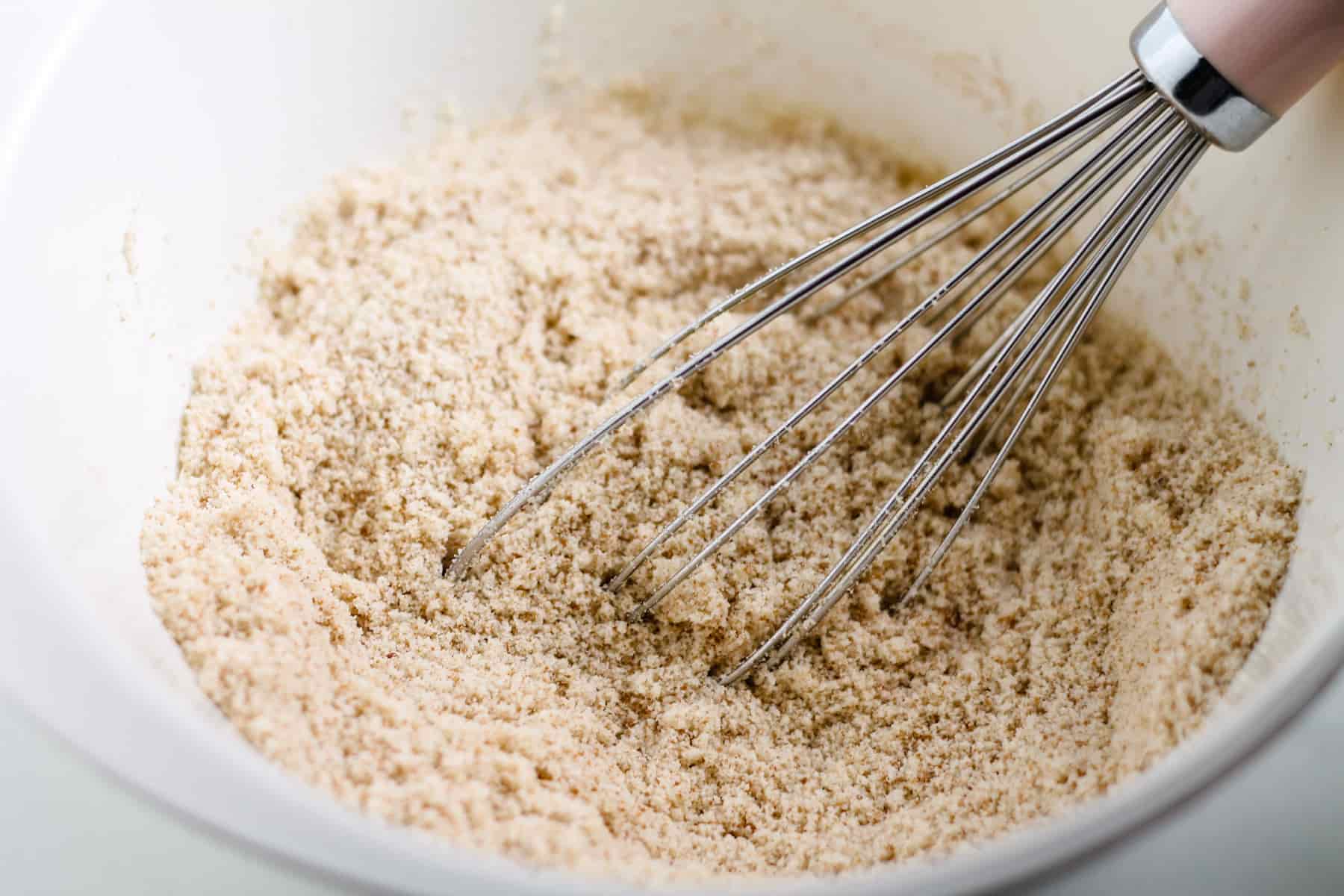 dry ingredients being whisked in a mixing bowl.