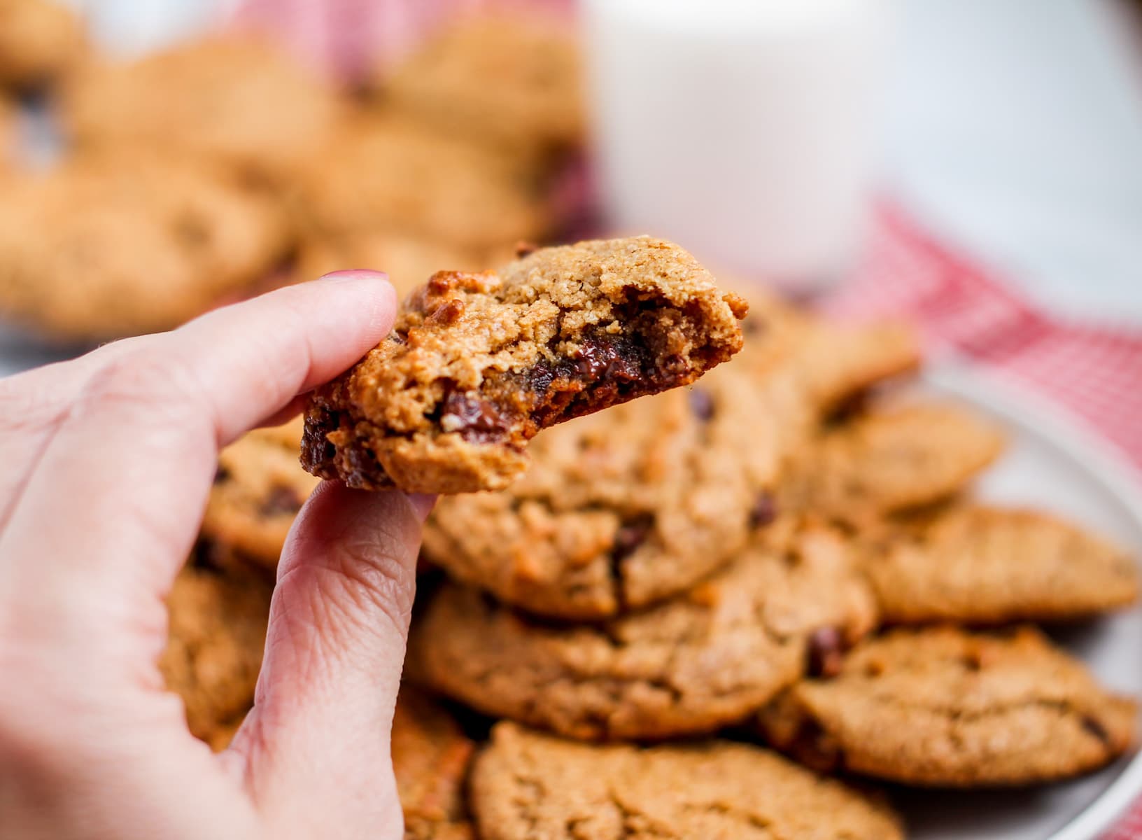 a hand holding a cookie with a bite out of it.