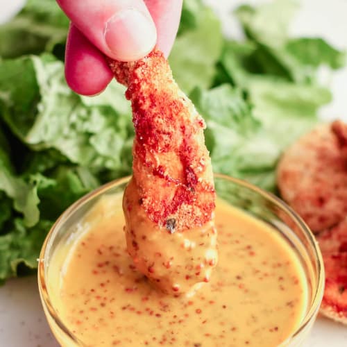 almond flour breaded chicken finger being dipped.