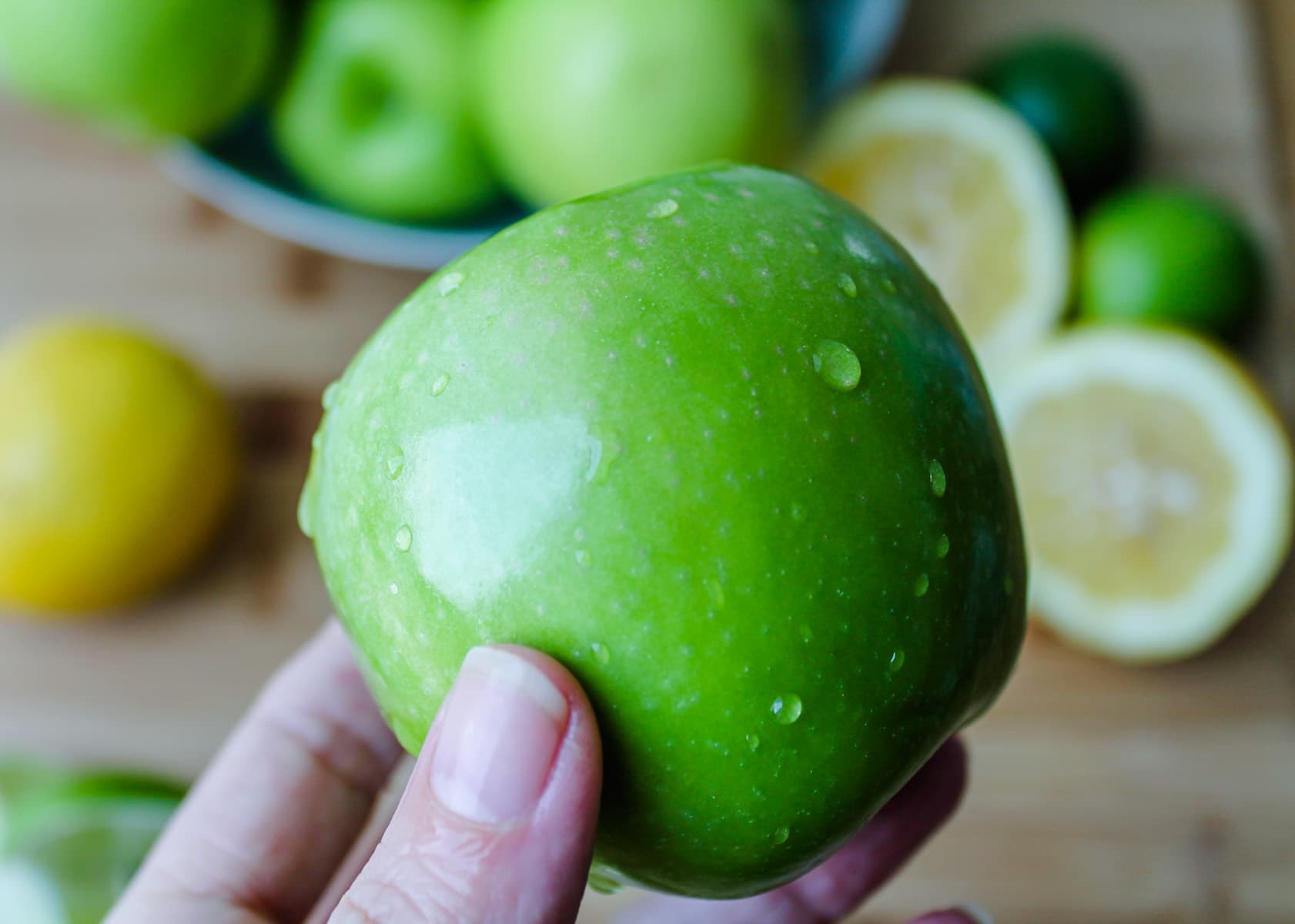 a hand holding a green apple.