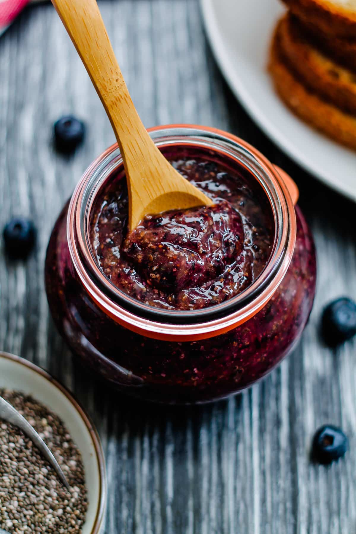 a wooden spoon scooping out some blueberry chia seed jam. 