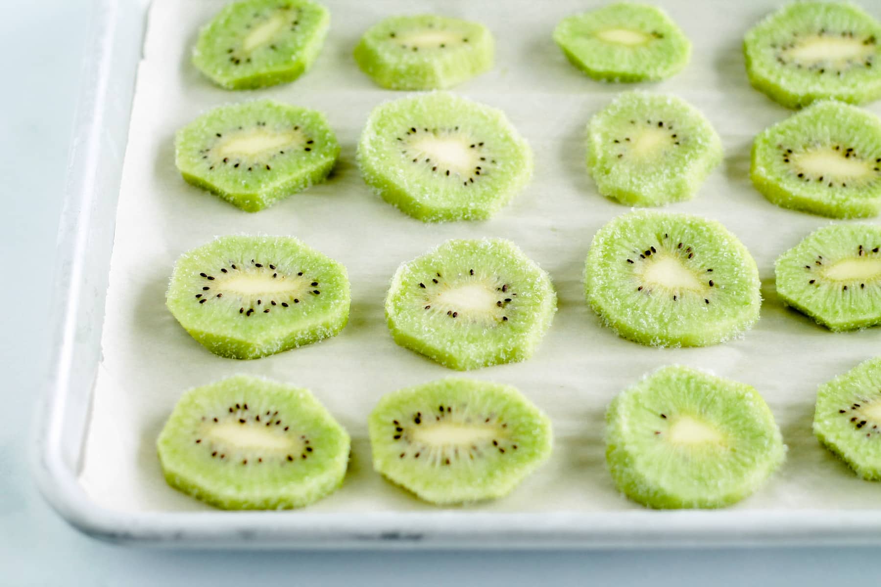 slices of frozen kiwi on a parchemnt lined tray.