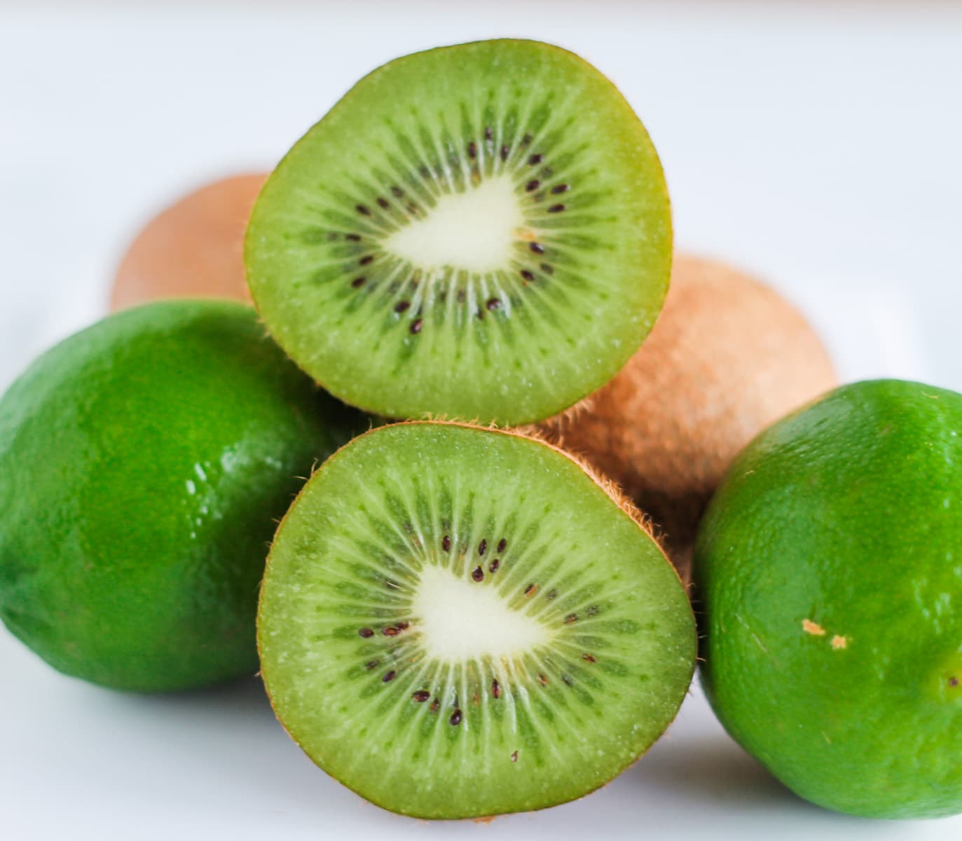 a pile of kiwi fruit with one sliced in half.