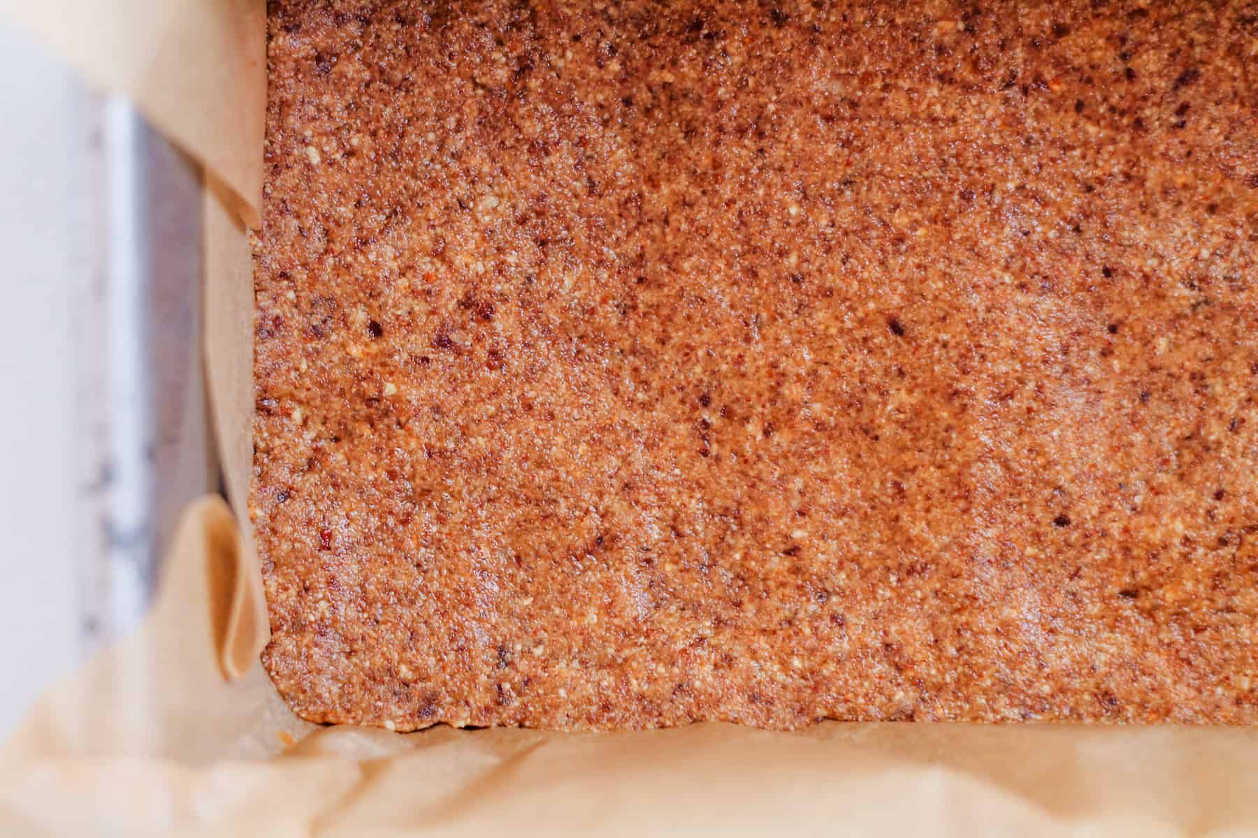 dough being pressed into a parchment lined loaf pan.