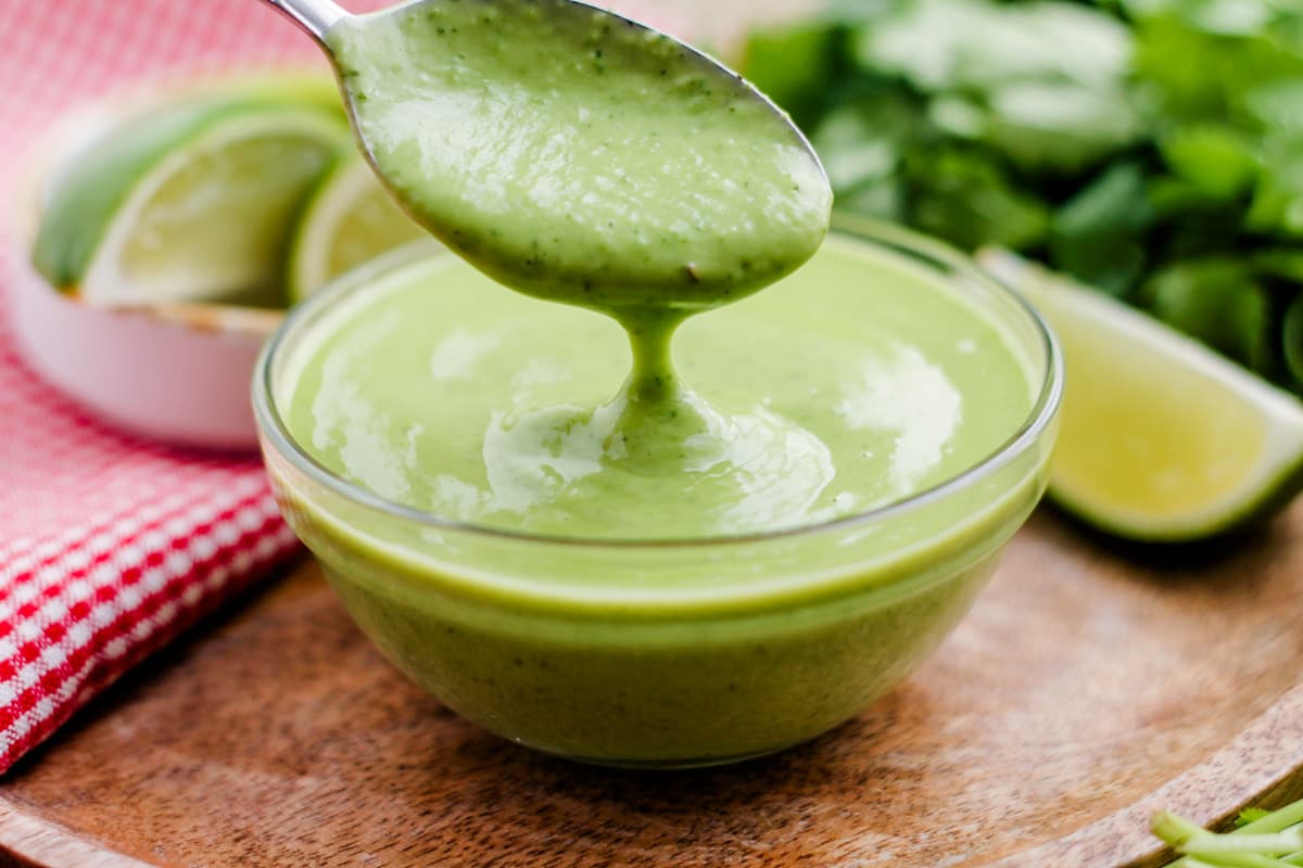 a spoon drizzling avocado cilantro dressing.