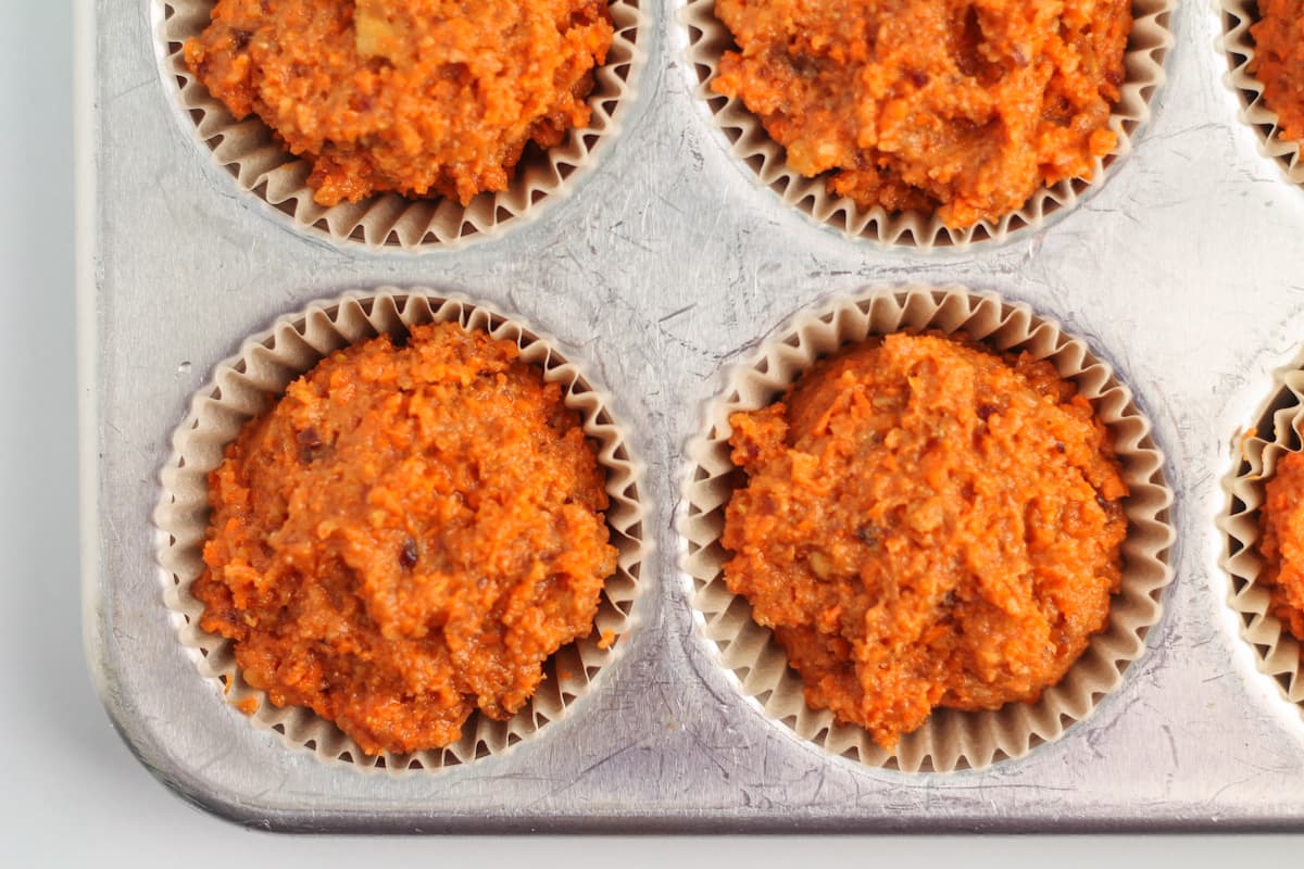 muffin batter scooped into a muffin tin.