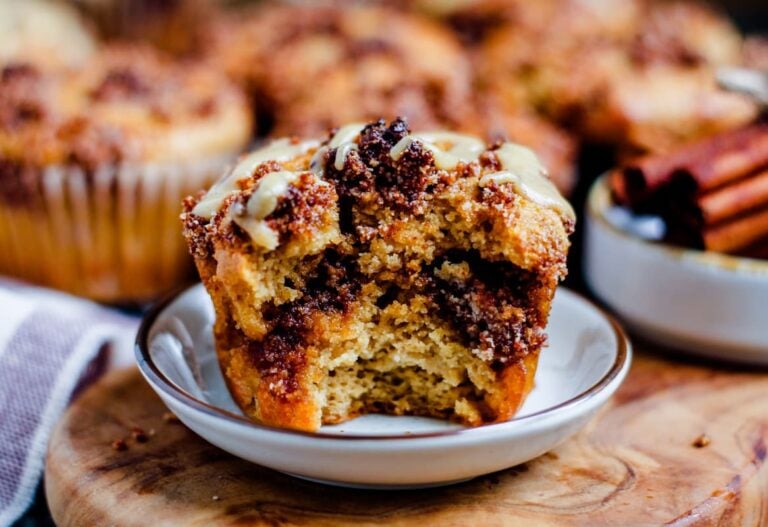 an almond flour cinnamon roll muffin on a plate with a bite out of it.