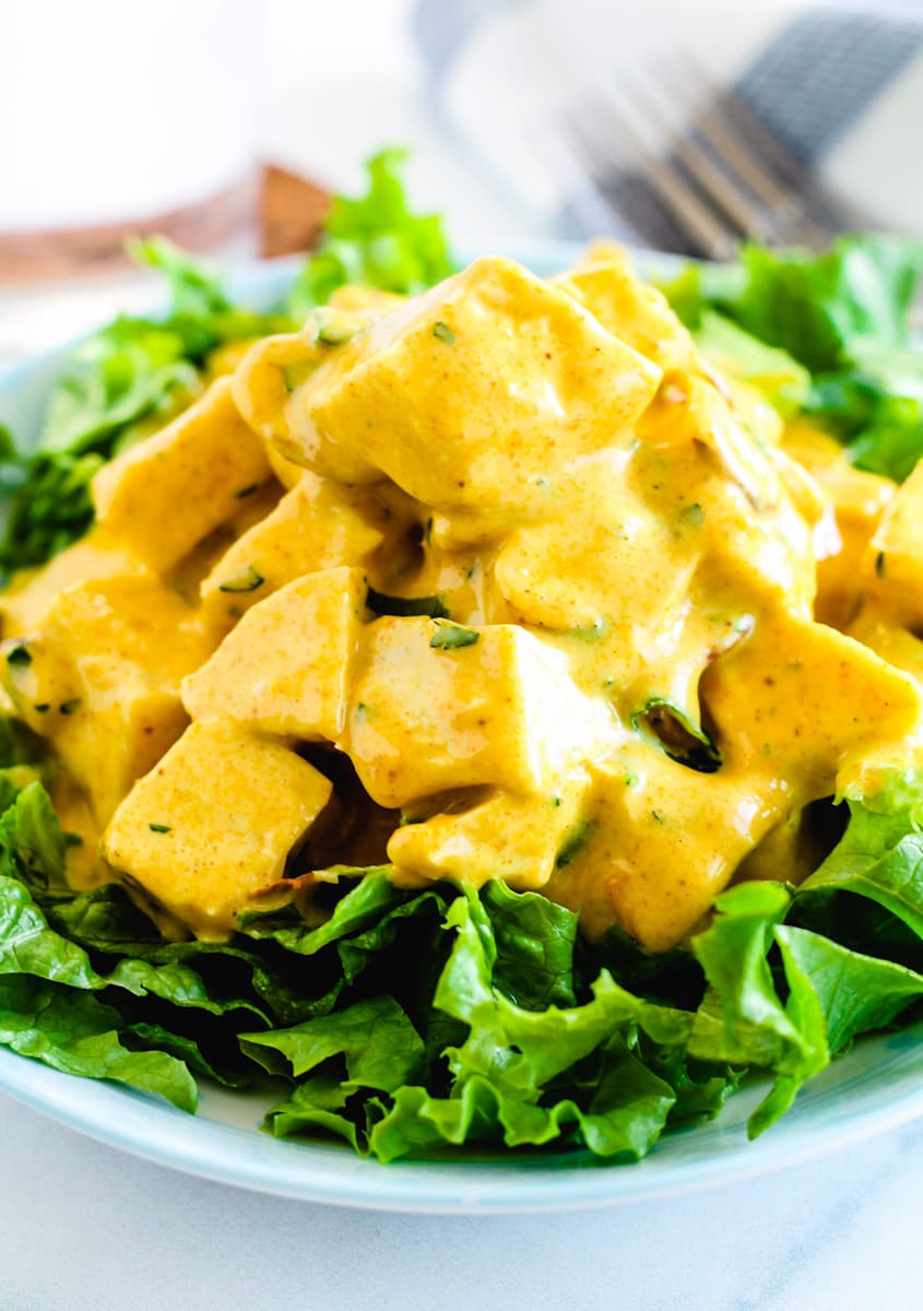 a plate of lettuce topped with coronation chicken salad.