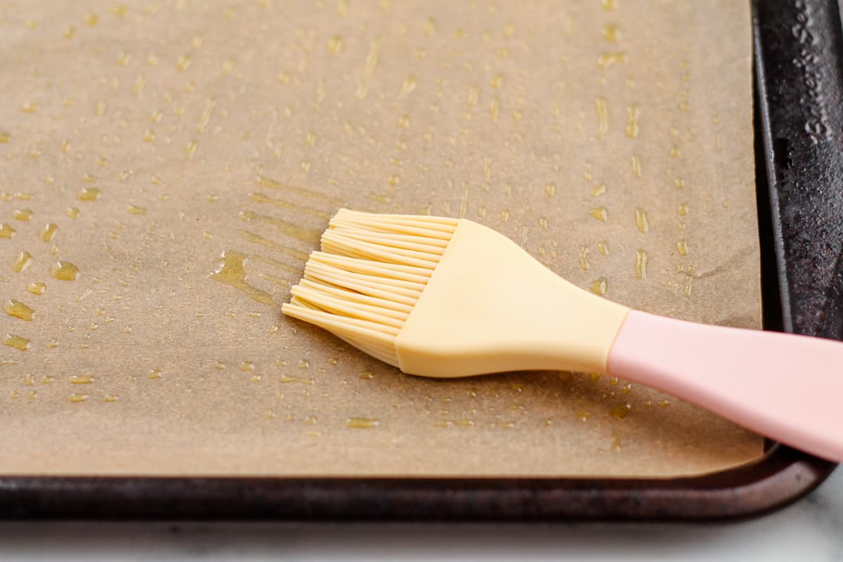 brushing oil onto a parchment lined baking sheet.
