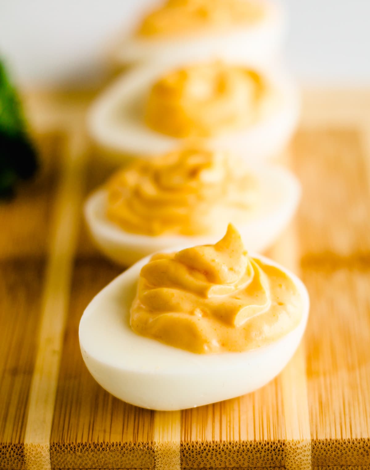 a row of hummus deviled eggs on a serving board.