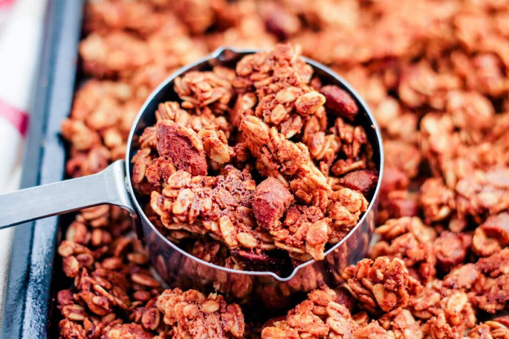 a scoop of vanilla almond granola from a baking pan.