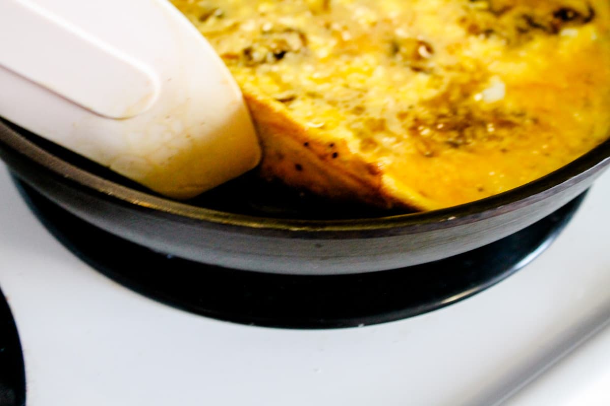 a spatula lifting up a cooked egg mixture in a pan.