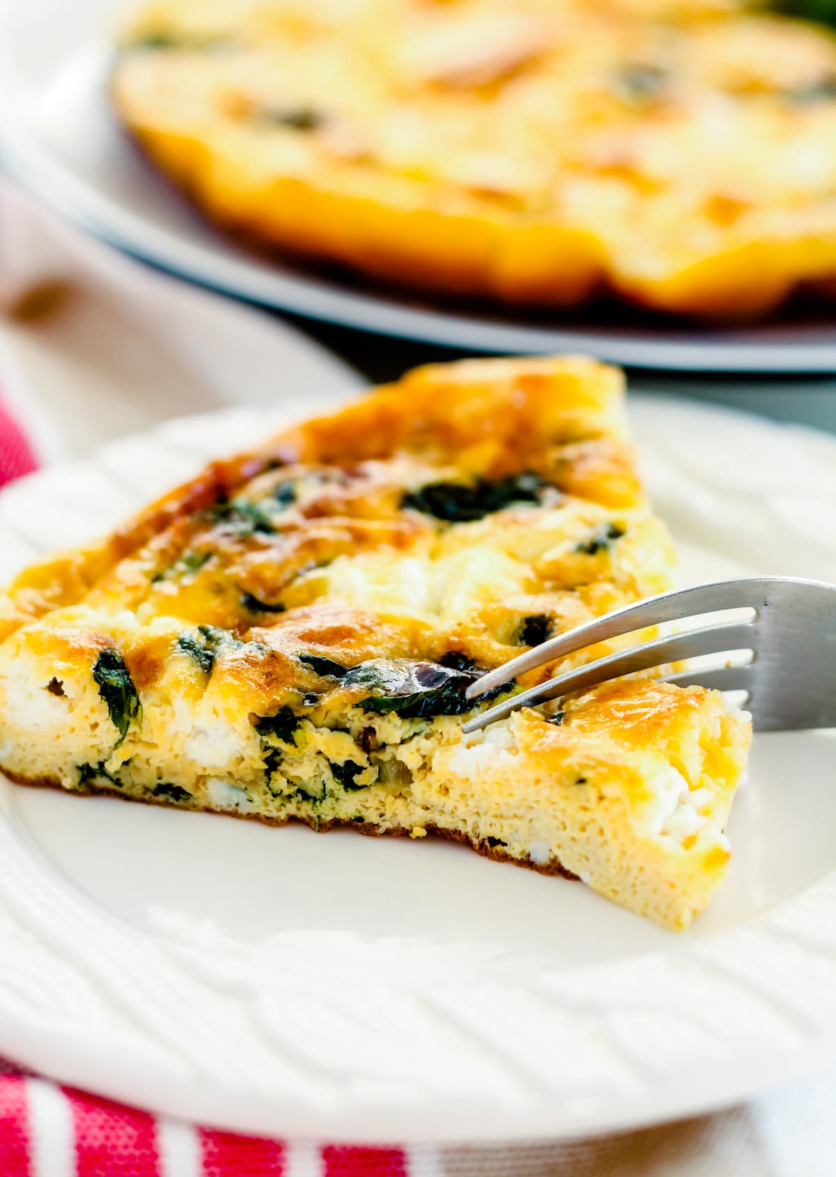 a fork slicing into a piece of goat cheese frittata.