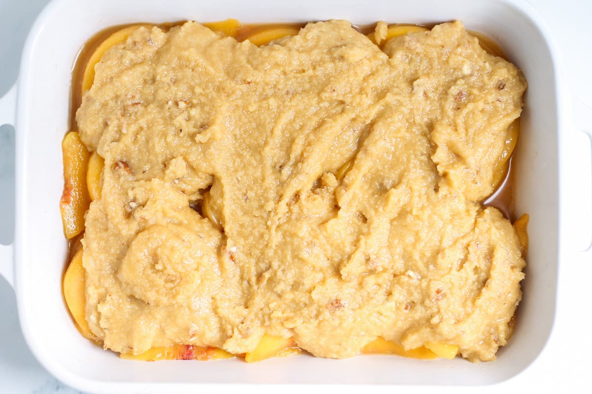 cobbler topping spread on top of peach filling.