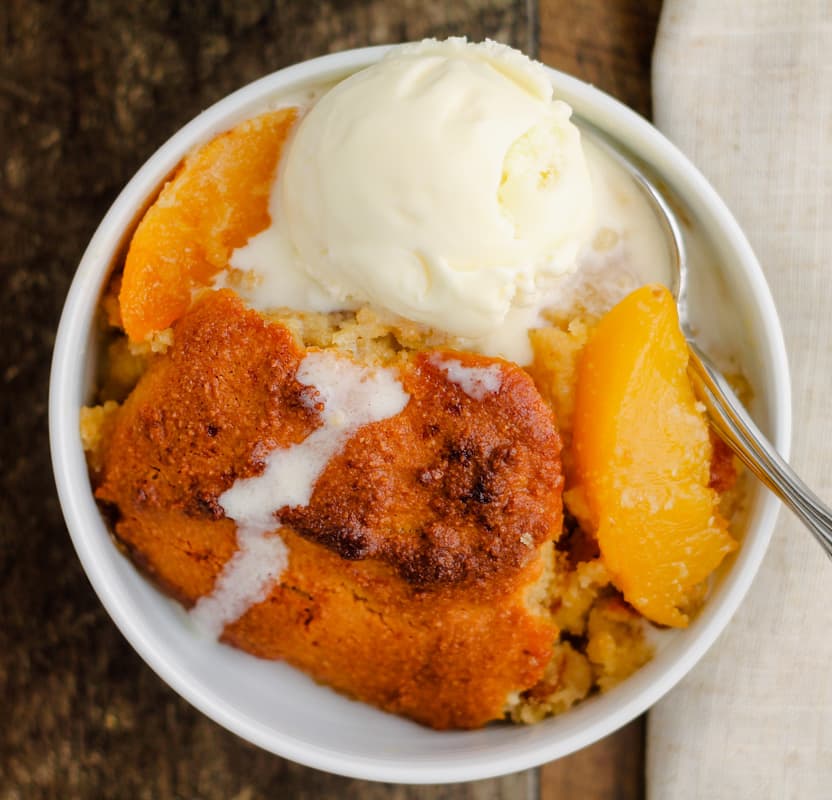 ice cream melting on a bowl of freshly baked healthy peach cobbler.