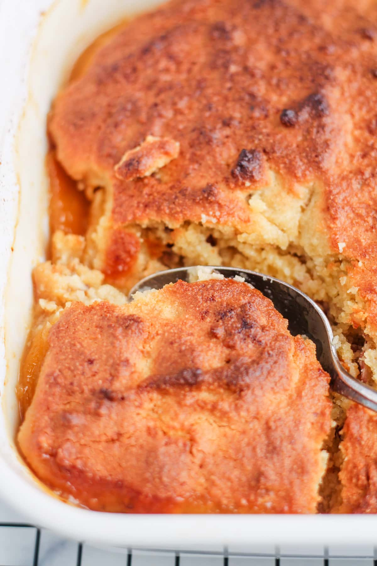 healthy peach cobbler being scooped with a spoon.