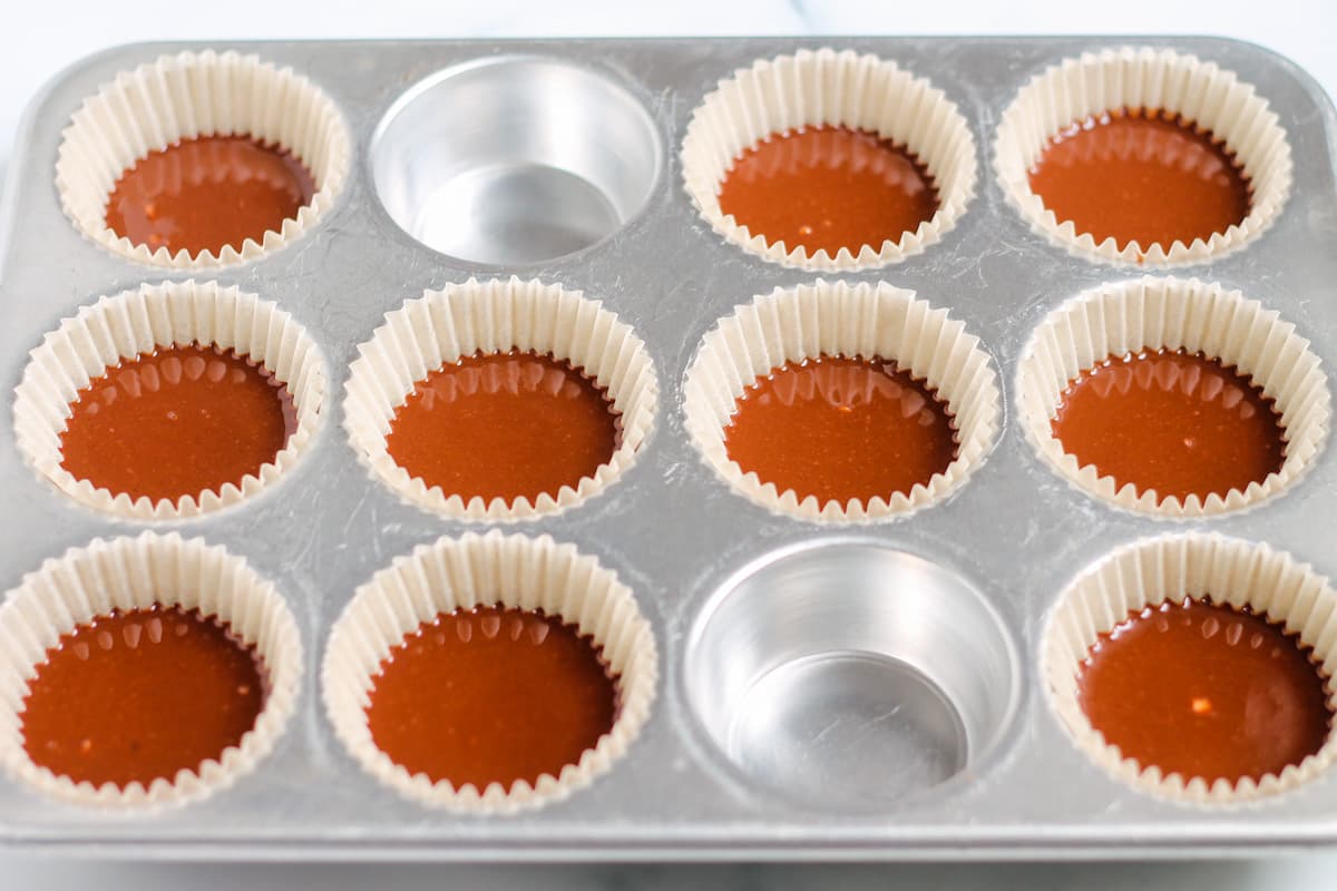A muffin tray filled with chocolate mixture.