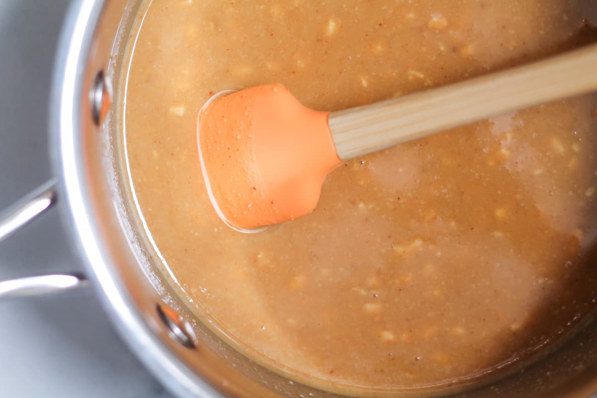 Peanut butter and coconut oil being stirred in a saucepan.